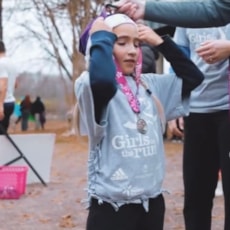 Girls on the Run participant high fives running buddy at 5K